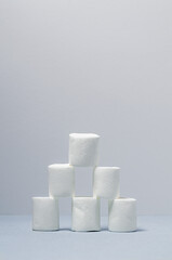 A pyramid of six white marshmallows on a blue background.