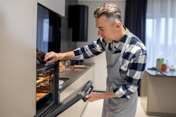 Man closing oven turning on regulating temperature