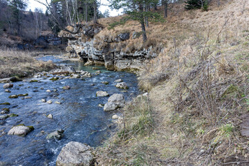 autumn morning, walking along the bed of a mountain river that has become shallow by the beginning...