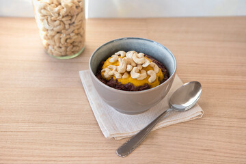 Vegan, gluten free food. Colourful porridge in bowl with cashew nuts topping on the wooden table....