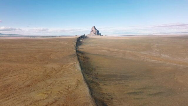 4K nature landscape with backbone hill in direction of Shiprock mountain visible remotely at the horizon line. Aerial Shiprock is dramatic geological wonder in deserted southwest of New Mexico, USA