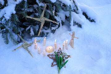 Wiccan altar for Imbolc sabbath, pagan holiday ritual. Brigid's cross of straw, candles, witchcraft doll, snowdrops on snow, winter forest natural background. symbol of Imbolc holiday, spring equinox. - obrazy, fototapety, plakaty
