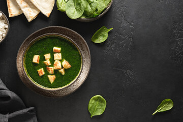 Palak Paneer served with basmati rice on black background. Indian vegetarian cuisine made of spinach and paneer cheese. Copy space. View from above.