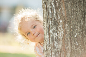 Cute little boy with curly blonde hair play hide and seek