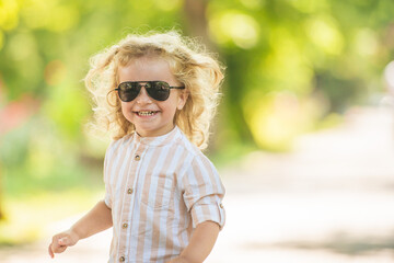 Cute little boy with curly blonde hair playing in park