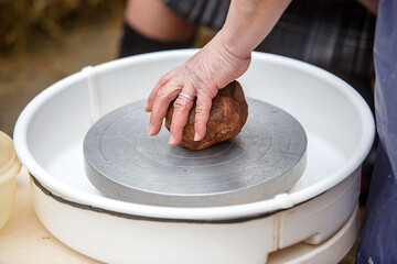 The pottery master kneads a piece of brown clay with his hands. Folk art.