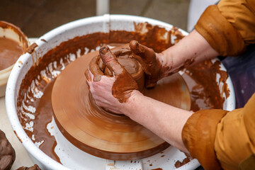 The master of pottery makes dishes from brown clay. Folk art.