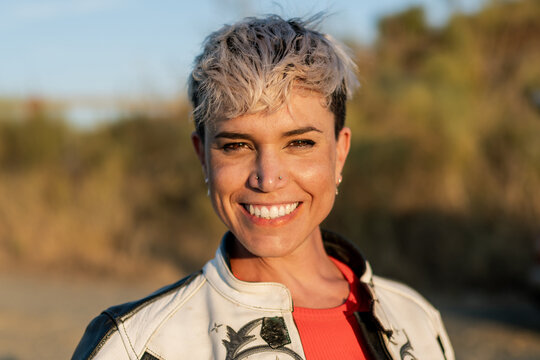 portrait of smiling young woman with blonde modern short haircut and earrings on her nose
