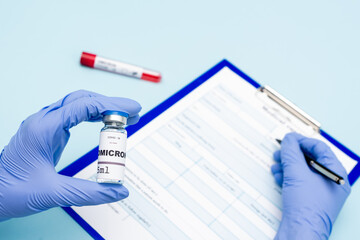 cropped view of immunologist in latex gloves holding covid-19 omicron variant vaccine and writing...