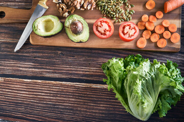 Variety of cut vegetables for a salad on vintage wooden background. Healthy vegetarian food, top view.