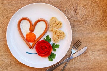 Heart shaped sausage and egg served with rose shaped tomato and heart shape whole wheat breads on...