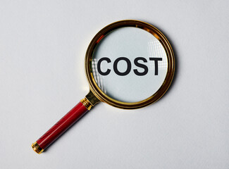 Cost word through magnifying lens on background.