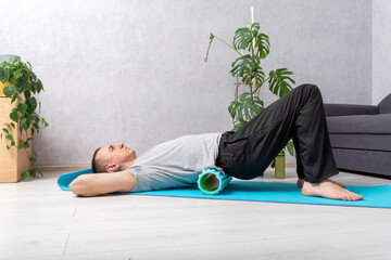 Man uses myofascial roller for back tension and muscle pain release. Man does self-massage of the...