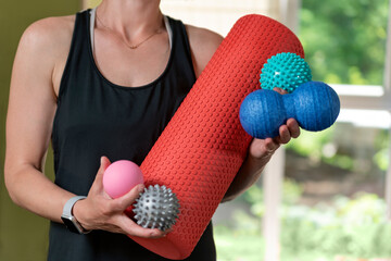 Young athletic woman holds equipment for MFR. Myofascial massage trainer. Different types myofascial rolls. © somemeans
