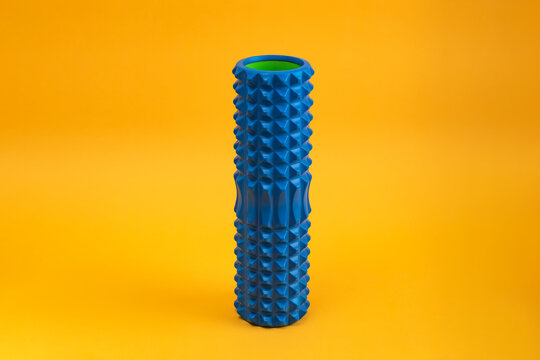 Tools for self-massage on yellow background. Foam roller for myofascial release. Massage roller.