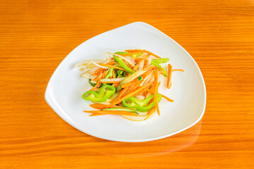 Assorted vegetables cut into strips and fried in a wok on a white plate