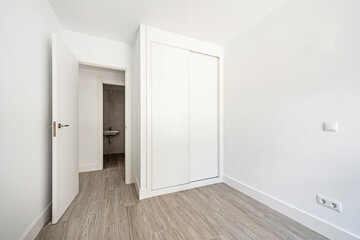 Room with built-in wardrobe with sliding doors and white wood carpentry with porcelain stoneware floors