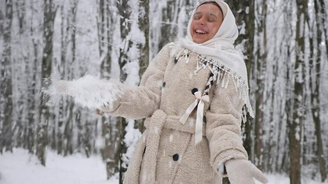 The girl throws up the snow in the woods. Slow motion.