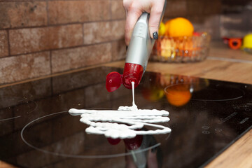 A young woman is cleaning an induction electric hob. Cleaning in the kitchen. Electric oven...