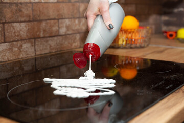 A young woman is cleaning an induction electric hob. Cleaning in the kitchen. Electric oven...