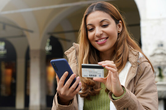 Close-up Of Business Woman Sitting On Bench Using Credit Card And Smartphone For Shopping Online Outdoors