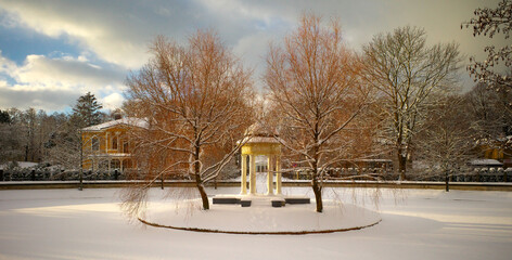 Atmospheric City winter landscape. Snow-covered pond and gazebo on the island.