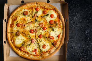 Vegetarian fresh pizza in an open box on a black concrete background. Top view, flat lay, selective focus, natural light