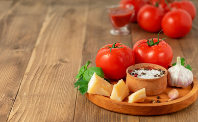 Tomatoes, parmesan cheese and spices on wooden background. Italian food concept, copy space.