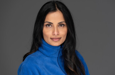 Fototapeta premium Studio headshot of beautiful Asian Indian woman on a plain background.