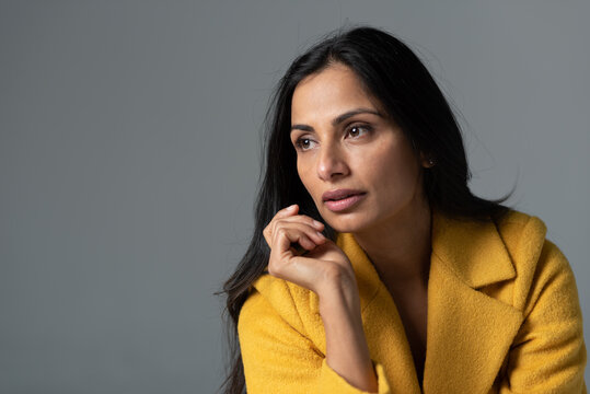 Studio images of beautiful Asian Indian woman in yellow coat. 