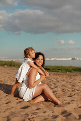 Fototapeta na wymiar mom and daughter of different nationalities play on beach in summer by sea