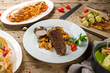 roast beef Steak, pork loin, spaghetti bolognese on wooden table side view