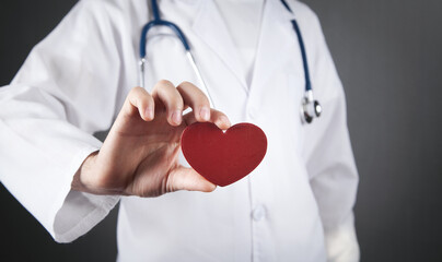 Doctor with stethoscope holding red heart.