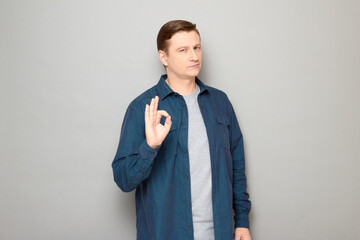 Portrait of confident mature man showing okay gesture and smiling
