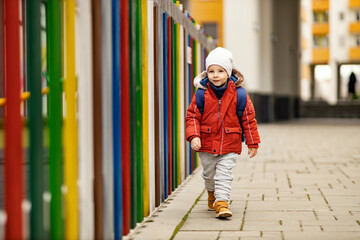 A 3-year-old kid on the street going to kindergarten.