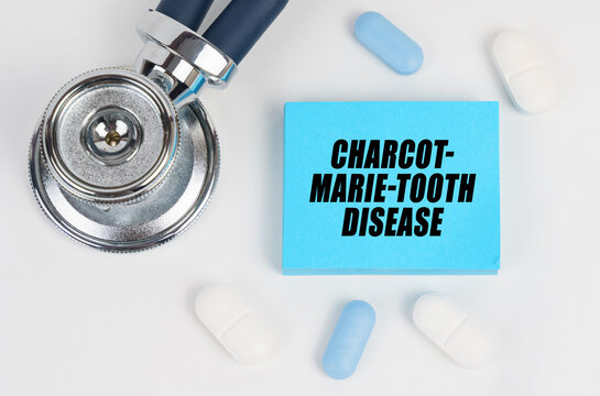 On a white surface lie pills, a stethoscope and stickers with the inscription - Charcot-Marie-Tooth disease - Powered by Adobe
