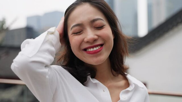 Charming young asian woman smile touch her hair Close up of happy lady outdoor in the urban city enjoy the day