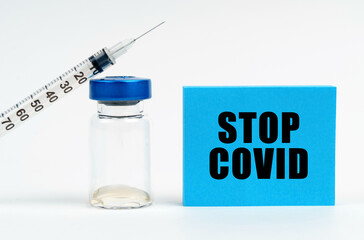 On the table is a syringe, an injection and a blue sign with the inscription - STOP COVID