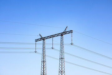 High Voltage Tower supporting an overhead power lines against blue sky