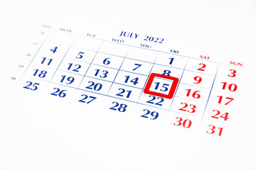 Calendar selective focused on 15 July 2022 (shallow depth of field) with red frame around 15 - Tax date deadline concept