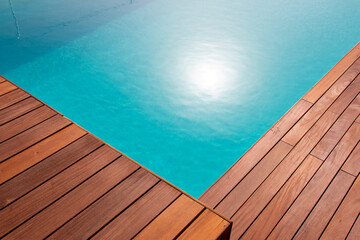 Diagonal lines of exotic hardwood in detail decking around the blue water swimming pool corner