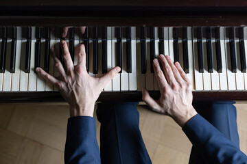 Hands of pianist man on the grand piano keyboard (high angle view from above)