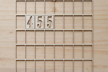 the number 455 in a wooden grid or frame on a wooden surface
