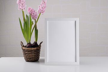 Portrait a4 white wooden frame mockup with pink hyacinth flower on the table on white wall of room. Poster mockup. Clean, modern, minimal frame. Empty frame Indoor interior, show text or product
