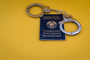 Passport of a citizen of the Republic of Belarus and handcuffs on a yellow background with copy...