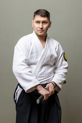Martial arts swordsman (aikido teacher) in traditional clothing holds his sword
