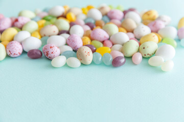 Fototapeta na wymiar Happy Easter concept. Preparation for holiday. Easter candy chocolate eggs and jellybean sweets isolated on trendy pastel blue background. Simple minimalism flat lay top view copy space