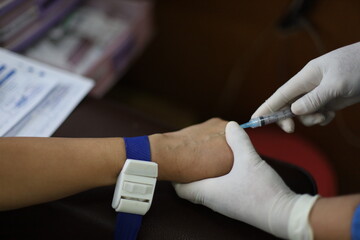 Close up Hand of nurse, doctor or Medical technologist in blue gloves taking blood sample from a...