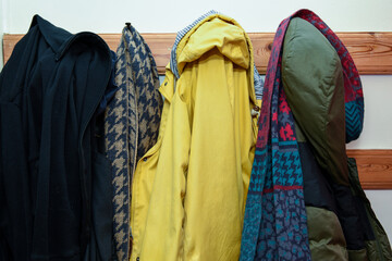 Coats and cold weather clothing in a a row in a family home - obrazy, fototapety, plakaty