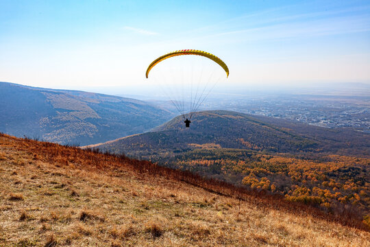 Paragliding over hills and autumn forest